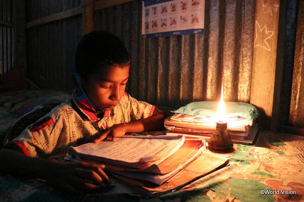 灯りのもと、自宅でも勉強に励むバングラデシュの少年