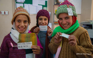 編み手の方の名前が書かれたネームプレートを見せてくれる女の子たち