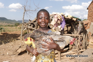 支援を通し飼育している鶏を抱きかかえるマラウイの子ども