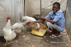 チャイルド・スポンサーシップによる支援で飼っている鶏を見せるコンゴ民主共和国の子ども
