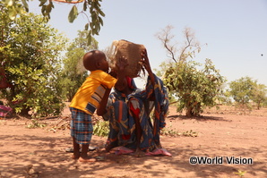 南スーダンの難民キャンプで木陰に座り水を飲む親子