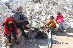 地震で被害を受け、がれきの中で暖を取るシリアの人々