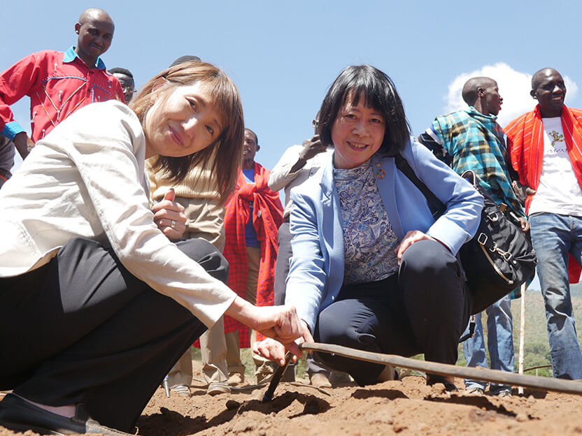 ソーラーポンプシステムでくみあげた水を活用する灌漑用の水道管を手に。福田氏（右）木内（左）
