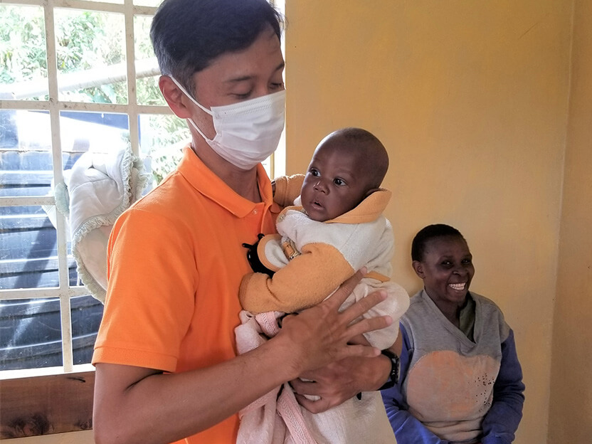 診療所で診察を待つ赤ちゃんを抱くWVJスタッフ