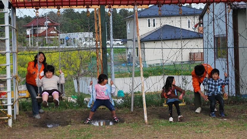 CFSでブランコで遊ぶ子どもたちとWVJスタッフ（2011年）