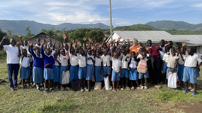 ケニアの事業地の小学校の子どもたちとWVJ遠藤スタッフ（後列オレンジ色のシャツ）