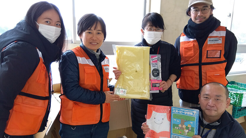 門前東小学校に防災頭巾や文房具をお届けした高橋スタッフ（左から2人目）