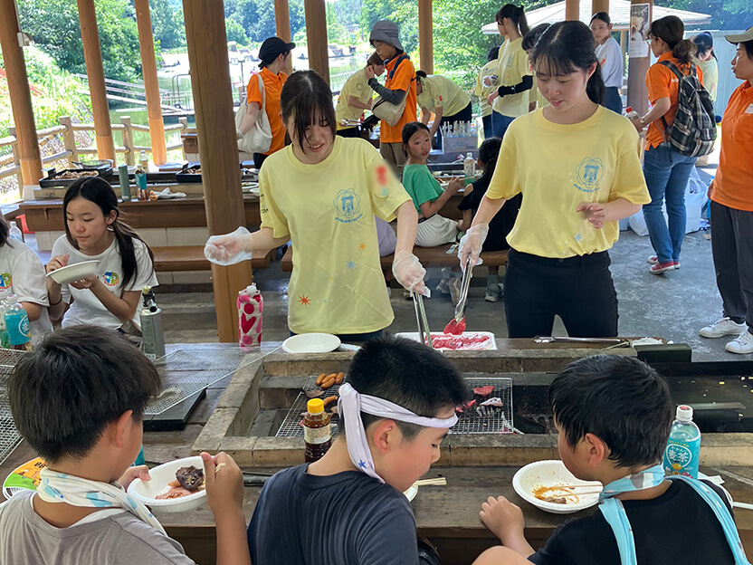 バーベキューを楽しむ子どもたちと大学生ボランティアの皆さん