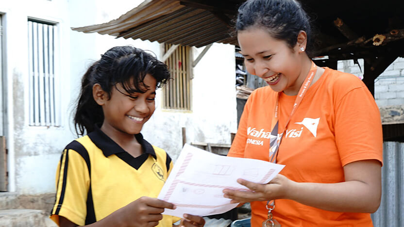 チャイルド・スポンサーからの手紙を読むインドネシアの少女とワールド・ビジョンスタッフ