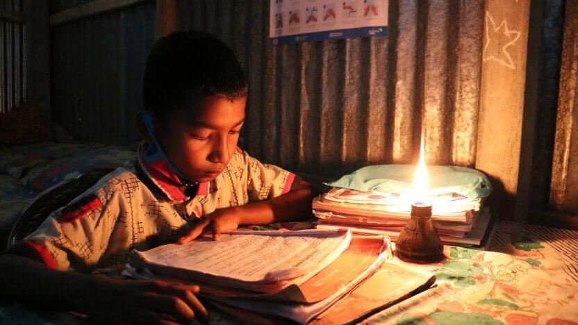 灯りのもと、自宅でも勉強に励むバングラデシュの少年
