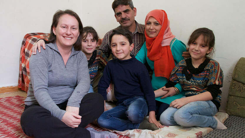 ヨルダンで暮らすシリア難民の家族とワールド・ビジョンのスタッフ。シリア難民の子どものうち85％(2018年時点)が貧困ラインを下回る生活を余儀なくされている