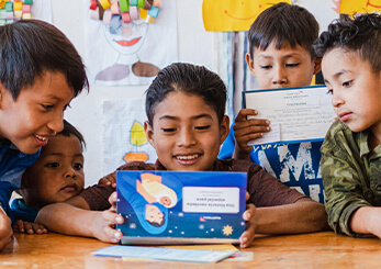 チャイルド・スポンサーから届いた手紙を囲み、支援を受ける子どもたちが笑顔で読んでいる様子。