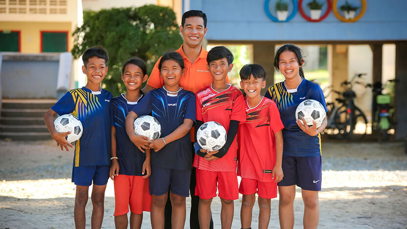 「『キャプテン翼』ボール」を受け取ったカンボジアのチャイルド・スポンサーシップによる支援地域の子どもたちとワールド・ビジョン・スタッフ
