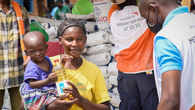 コンゴ民主共和国東部ミノヴァの国内避難民支援センターで穀物・油などの支援を受け取ったシファさん（28歳）とアマちゃん（1歳）。シファさんはマシシでの戦禍を逃れ、夫と7人の子どもたちとともに避難してきました