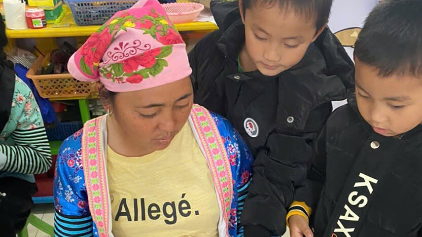 左記セッションで配られたハンドブックを読む母親と子ども（幼稚園）