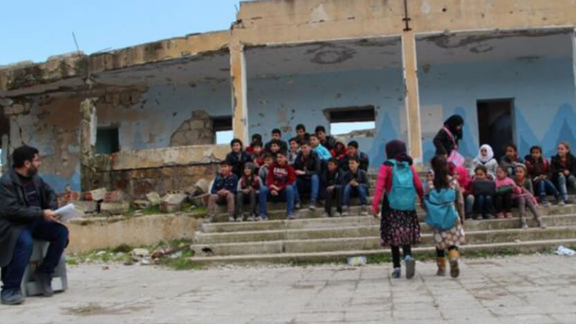 屋根も壁もない校舎で学ぶ子どもたちと先生