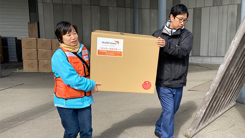 仮設住宅に寝具セットを運びこむ輪島市防災対策課の堤さま(右)とWVJ高橋