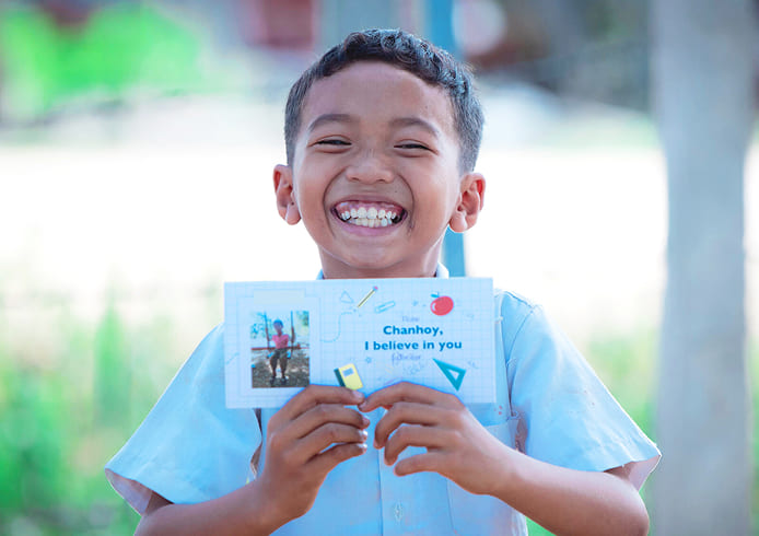 チャイルド・スポンサーからの応援メッセージに感激し、笑顔でカードを掲げる子ども。