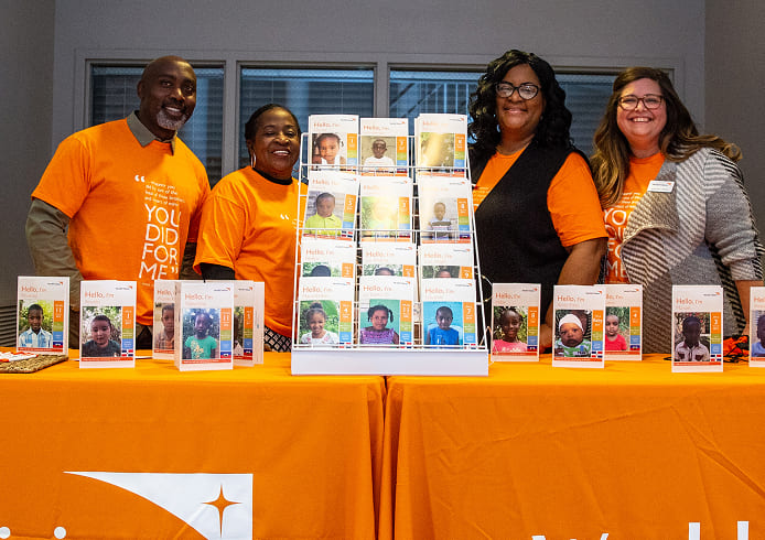 チャイルド・スポンサーシップへの参加を呼びかけるブースで、支援を紹介するスタッフたちが笑顔で来場者を迎える様子。