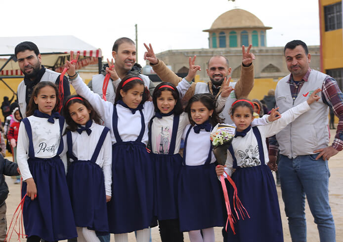 教育支援の現場で、子どもたちとワールド・ビジョンのスタッフが未来への希望を胸に笑顔を交わす様子。