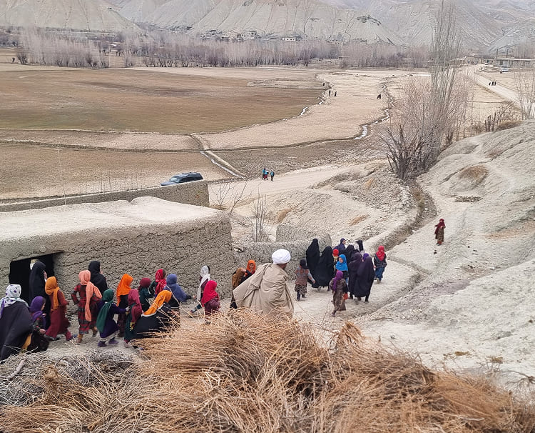 乾燥地帯の山道を歩き学校に向かうアフガニスタンの子どもたち。教育支援により広がる未来への道。