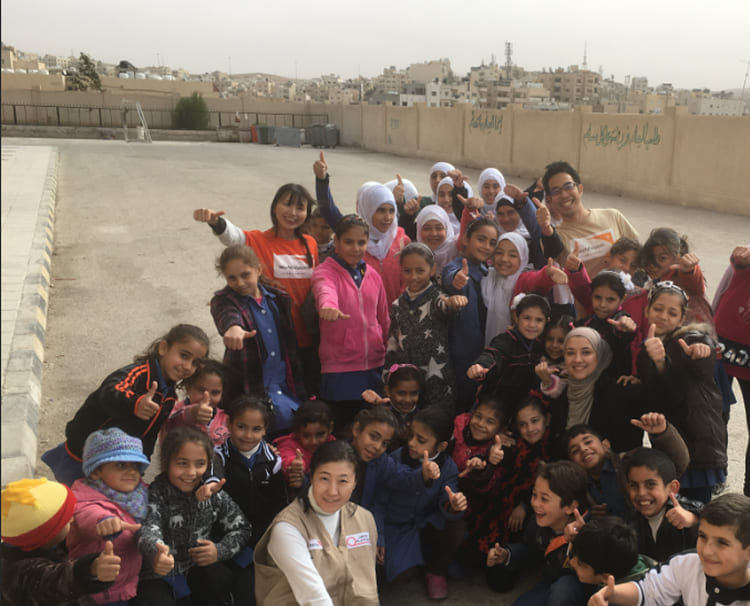 屋外で支援スタッフと子どもたちが親しげに笑い合う。教育支援の成果としての信頼関係と安心感が伝わる瞬間。