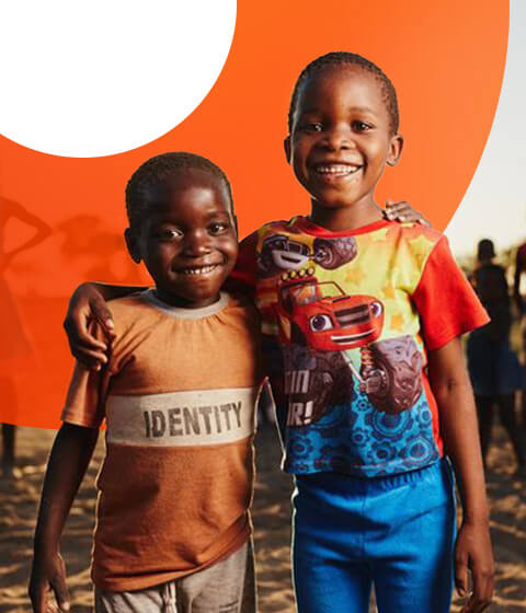 チャイルド・スポンサーシップを通じて希望を育むアフリカの男の子2人が、元気な笑顔で寄り添う場面。