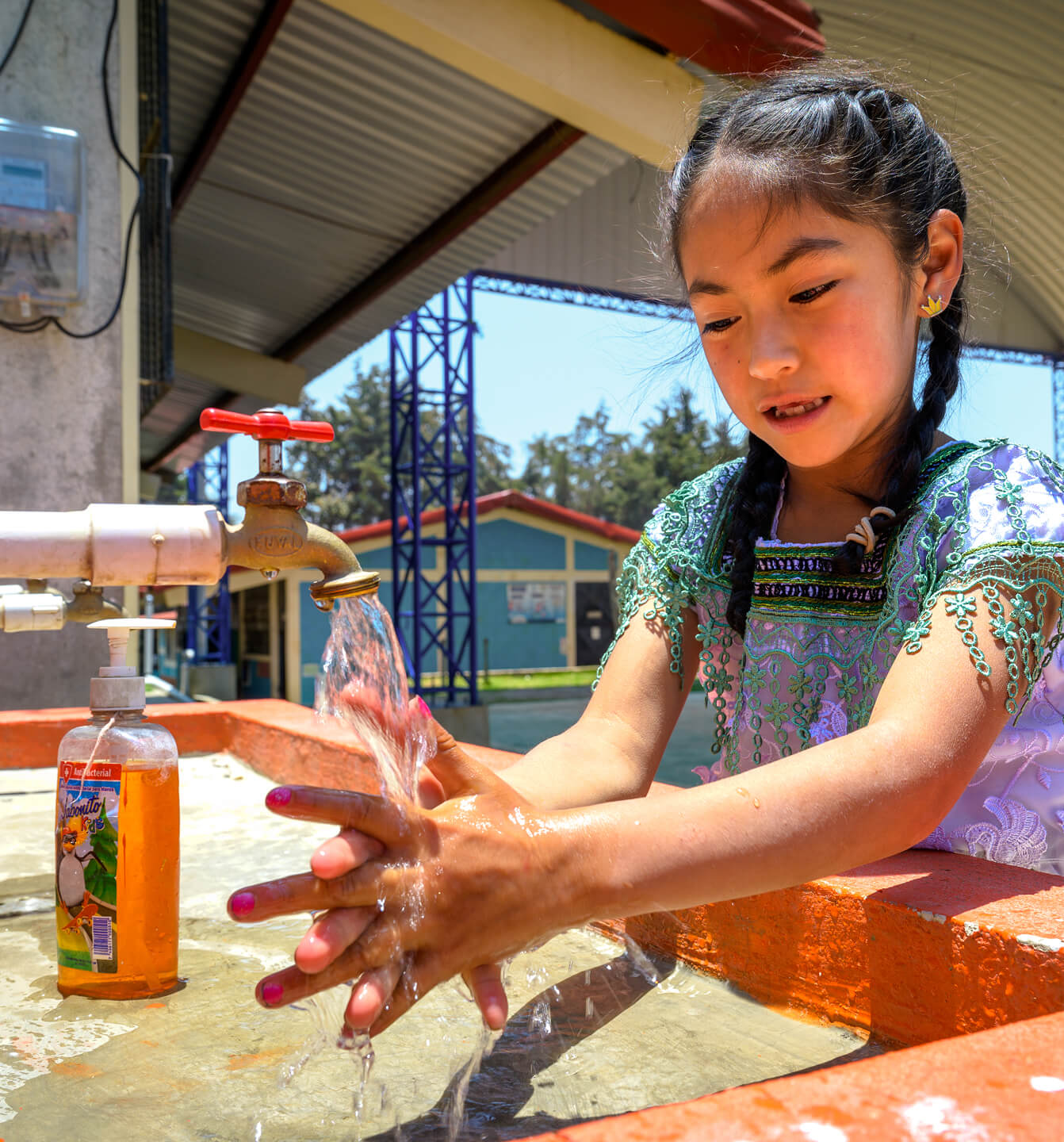 石けんを使い流水で手洗いする女の子。安全な水と衛生教育の支援が、感染症予防と健康促進に不可欠であることを示す情景。
