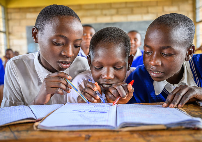 教育支援を受けた子どもたちが教室で協力し合い、真剣に課題に取り組んでいる。