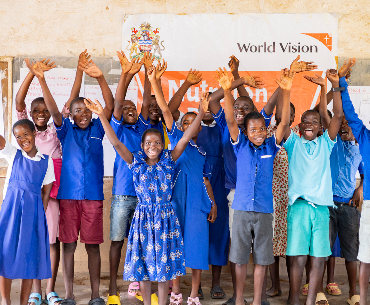 ワールド・ビジョンの支援を受ける子どもたちが、仲間と共に笑顔で手を挙げ、喜びを分かち合う。