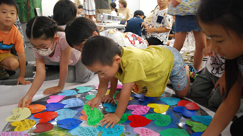 メッセージを書いて地球に貼る小学生の皆さん