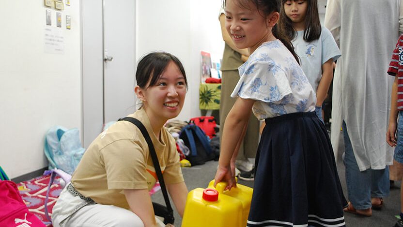 怪我なく水汲み体験ができるようサポートをするユースボランティアの大学生