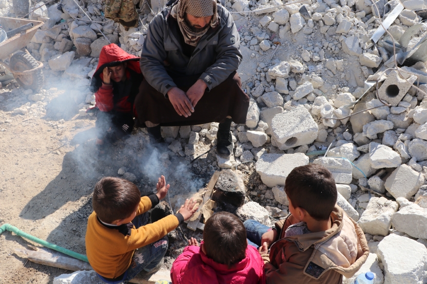 地震の直後、がれきの中で暖をとる人々