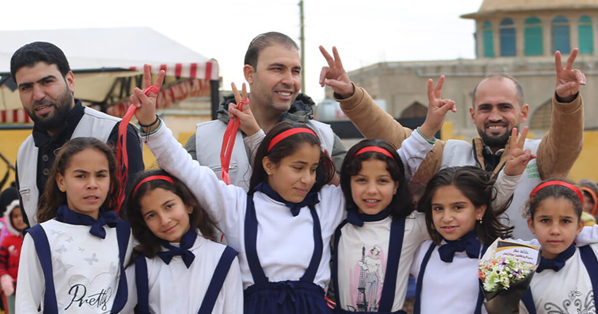 教育支援の現場で、子どもたちとワールド・ビジョンのスタッフが未来への希望を胸に笑顔を交わす様子。