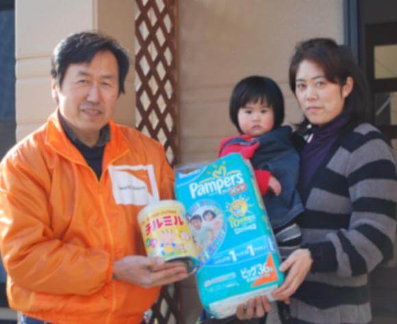 ご提供いただいた支援物資を手渡す、高木スタッフ