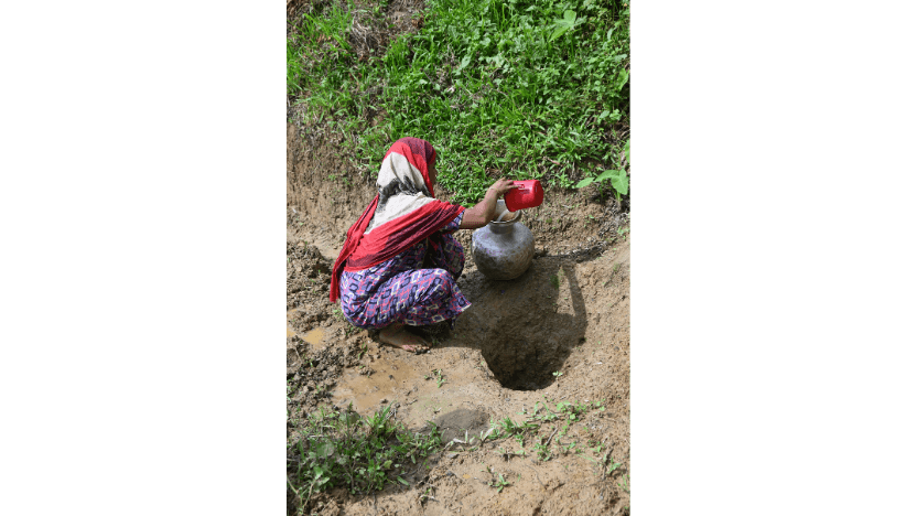 不衛生な水溜まりから水を汲む女性