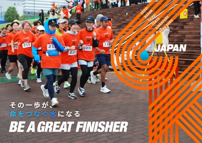 Group of runners in orange shirts start a race on a brick plaza, beside a bold orange graphic design and the word 'JAPAN'.