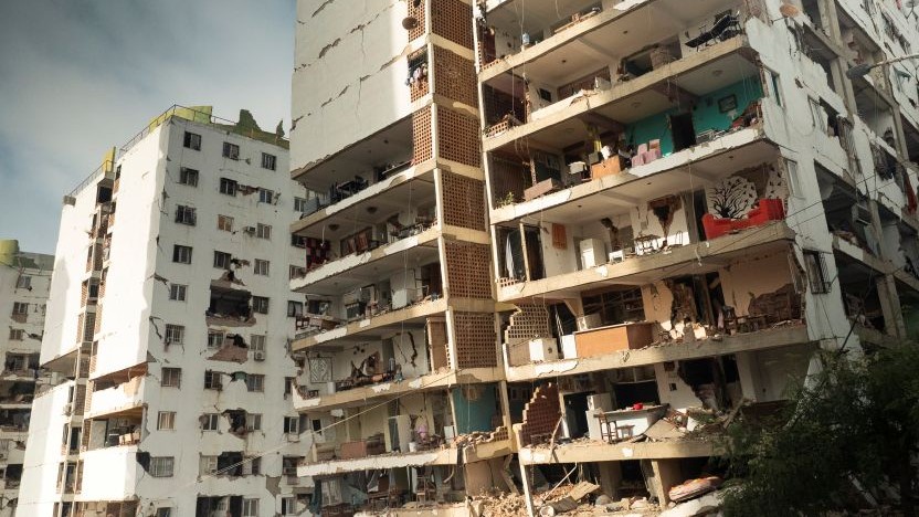 Ruined high-rise apartment building with exposed interiors and rubble after a disaster or explosion cleanup view?