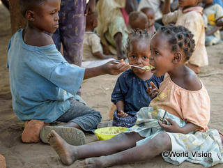 貧困のため食べ物が十分になく、わずかなお粥を分け合う兄妹（コンゴ民主共和国）