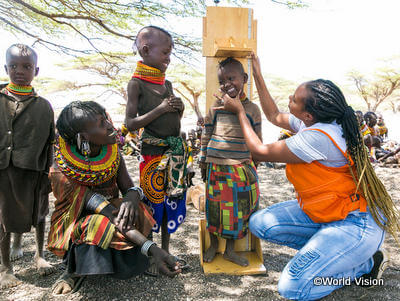 身長を測り、成長を確認するWVスタッフと子ども(ケニア)