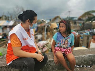 沿岸部で台風「ゴニ」の被害を受けた子どもと、寄り添うWVのスタッフ