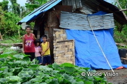 台風で家を失ったノルマさんと2人の子どもたち。今は防水シートで修復した近所の人の家に身を寄せていますが、WVからシェルターの支援を受けることが決まっています(2014年3月)