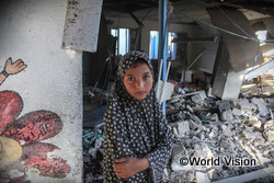 爆撃された教室の前に立つ少女。ここで12人が死亡した